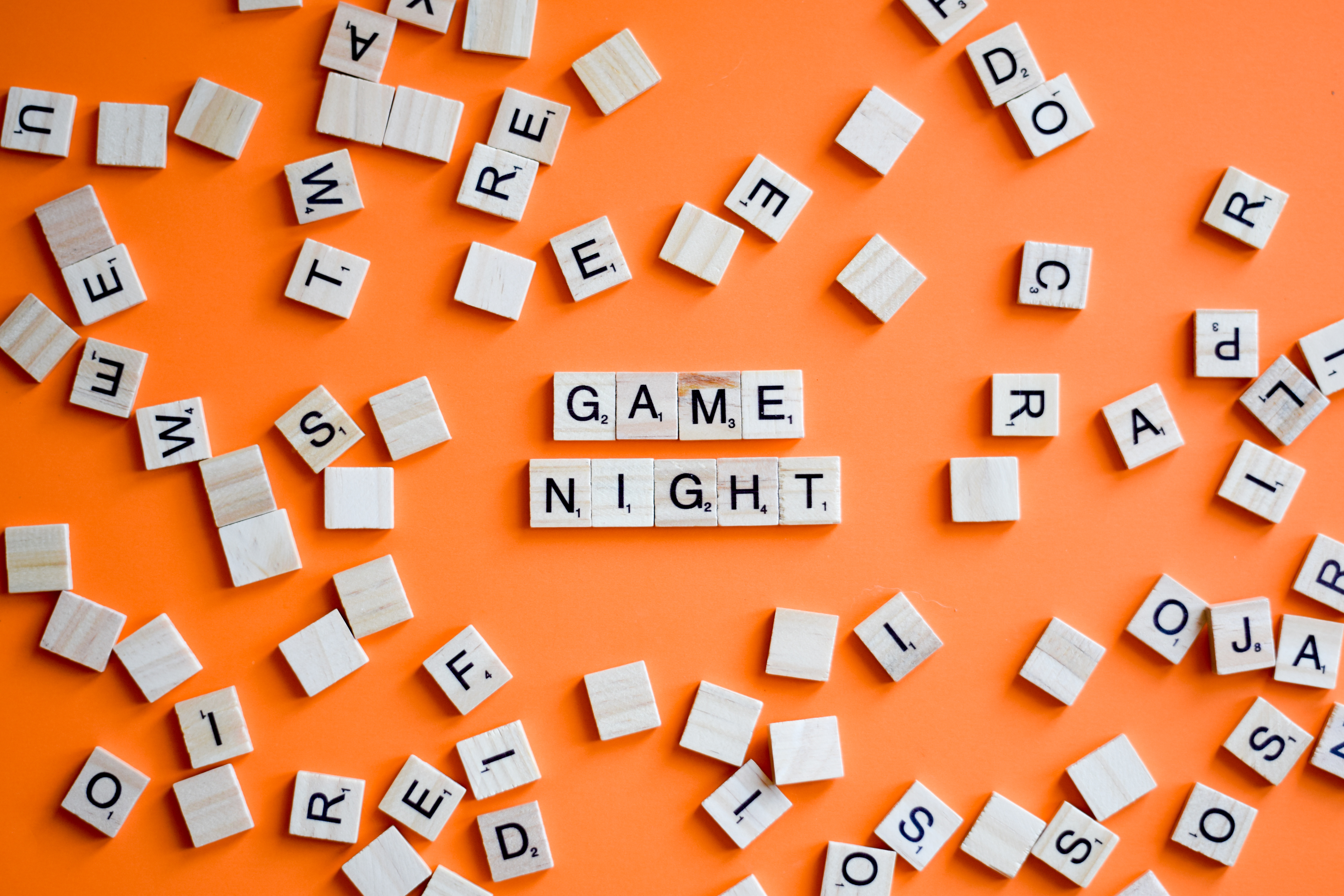 Scrabble letters on orange background spelling words GAME NIGHT